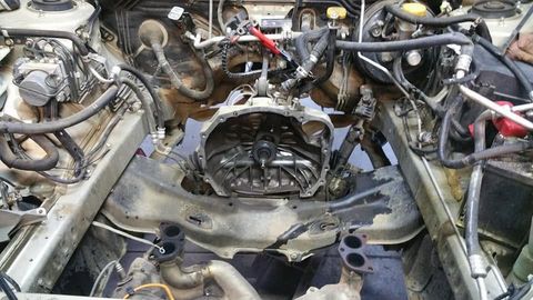 Engine bay with the engine out, showing the transmission bell housing and clutch during a clutch job