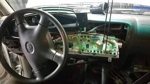 Toyota truck dashboard taken apart with the instrument cluster circuit board exposed for electrical repair