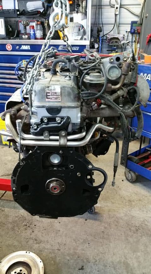 Rebuilt Toyota 22RE four-cylinder engine hanging from a hoist chain in front of a Snap-on toolbox